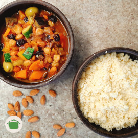 Imagem: Uma tigela de cerâmica à esquerda servada com couscous e outra mais acima servida com os legumes, entre elas amêndoas.