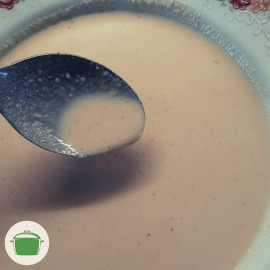 Imagem: Creme para empanar reservado em um prato fundo, uma colher é usada para mostra o molho em destaque